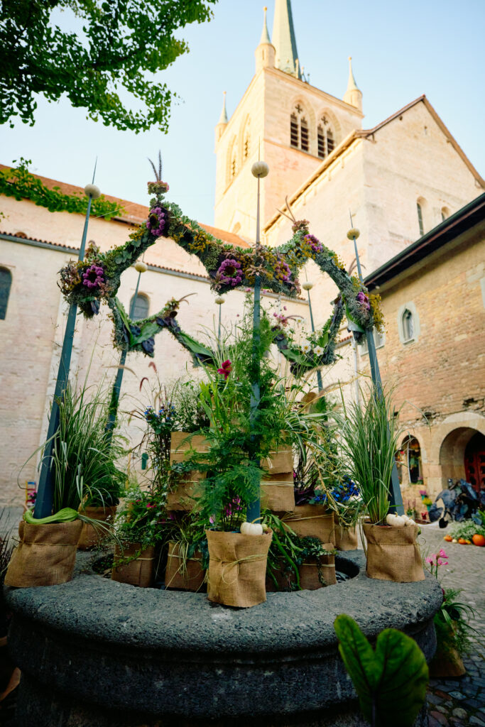 Installation végétale autour du puits dans la cour du Château avec l’Abbatiale de Payerne en arrière-plan lors de De Vert et d’Art 2024
